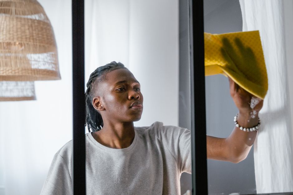 A man cleaning a window with a yellow towel, focusing on indoor chores.